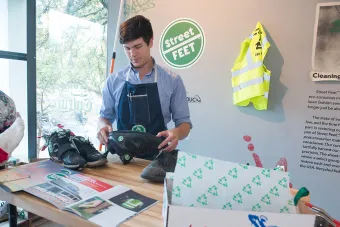 Henry Smith works on shoes as part of an art exhibition.