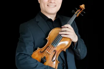 Wei He poses with a violin