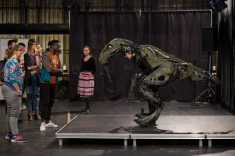 UT students examine an animatronic raptor costume worn by another student