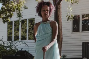Gesel Mason wearing a blue dress posing outside while doing research for her project YES, AND