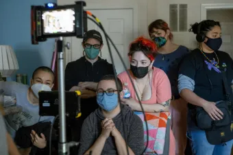 Filmmaker Lane Michael Stanley sitting with the production team for one of their films, looking joyfully at the camera screen