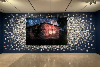 Large wall display of photography collage with a single large photograph of a home in the center