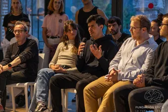 Daniel Ruiz Bustos sits with a group of fellow artists, speaking into a microphone and looking forward