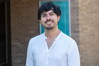 Daniel Ruiz Bustos smiling in front of a brick building