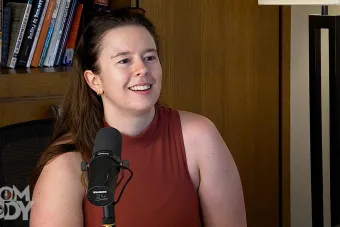 Maria Parrini sitting and talking into a mic with a bookshelf in the background