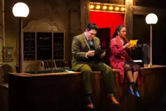 Photo of a man and a woman in 20th century clothing sitting on a desk