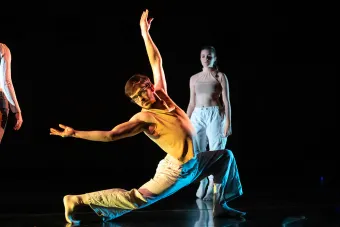 A student dancer lunges forward with arms outstretched