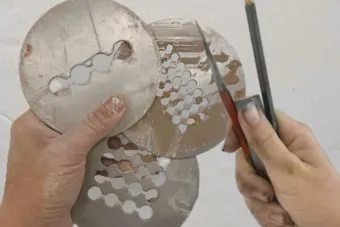 Metal disks and compass and pencil held by two hands