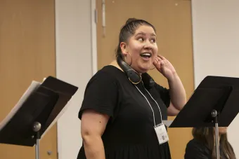 Lily Guerrero holds her hand up to her ear in "listen" gesture at a Meet the Opera program
