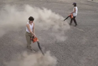 image of two people in the desert with leaf blowers