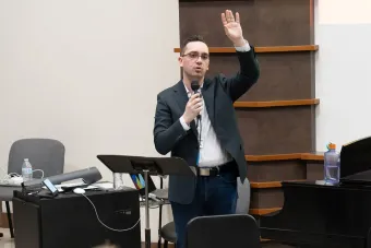 Presenter talks into a mic with a hand raised