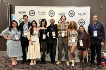 A group of people pose for a picture in front of a NATS background