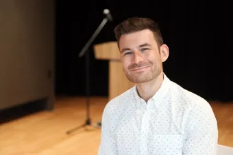 Tyler Ehrlich with a mic and podium in the background