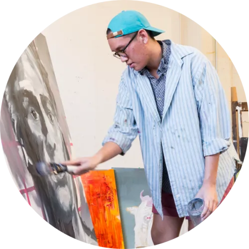 A student painting in front of an easel.