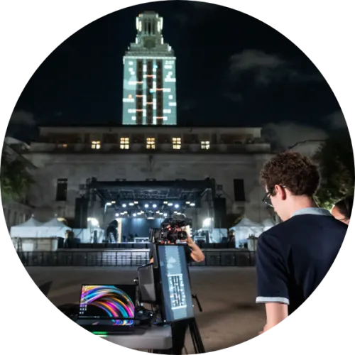 A video game is projected on the UT Tower as participants play the game.