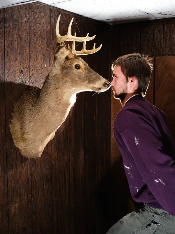 image of person nose-to-nose with taxidermied deer head on wall
