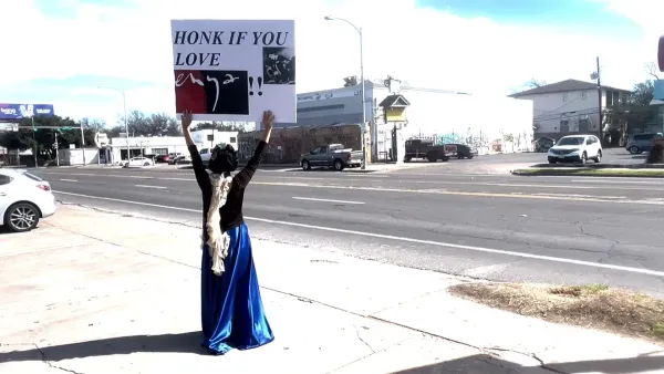 person holding sign on side of street