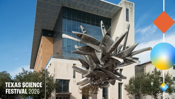 A sculpture of amalgamated aluminum canoes are suspended in front of a building.