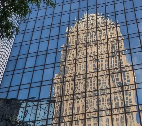 glass facade of modern building reflecting historic structure