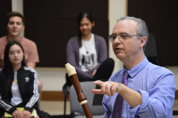 Man with Oboe addressing a crowd of students who watch with wrapped attention