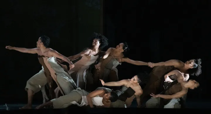Seven dancers positioned as if they were holding onto each other