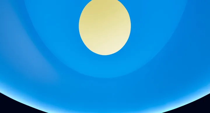 A blue lit curved interior features a circular oculus at the top that opens to a yellow sky.
