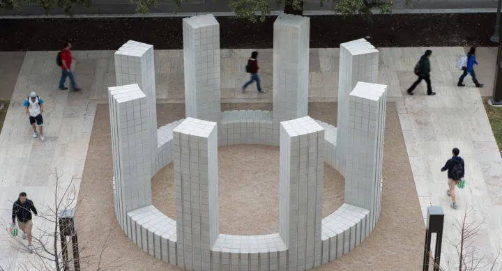 A large exterior sculpture made of cement, arranged in a circle with columns  