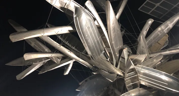 Nighttime view of a large sculpture made of metal canoes