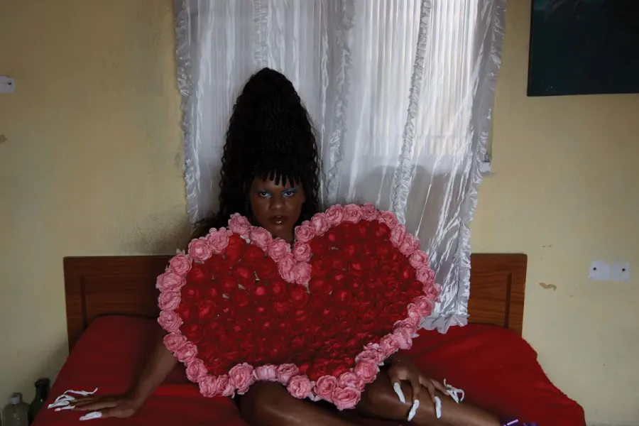 person laying on bed holding red and pink heart piece