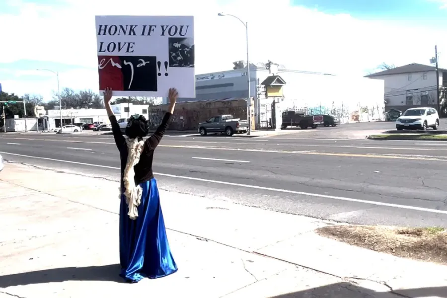 person holding sign on side of street